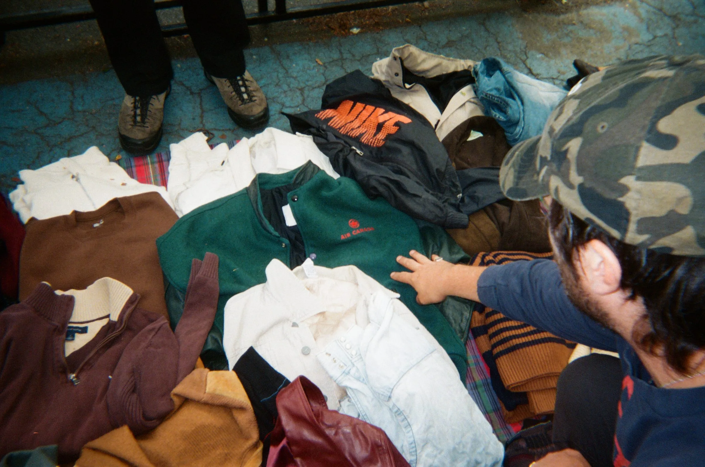 A reseller sorting sweatshirts and polo shirts laid out on the ground