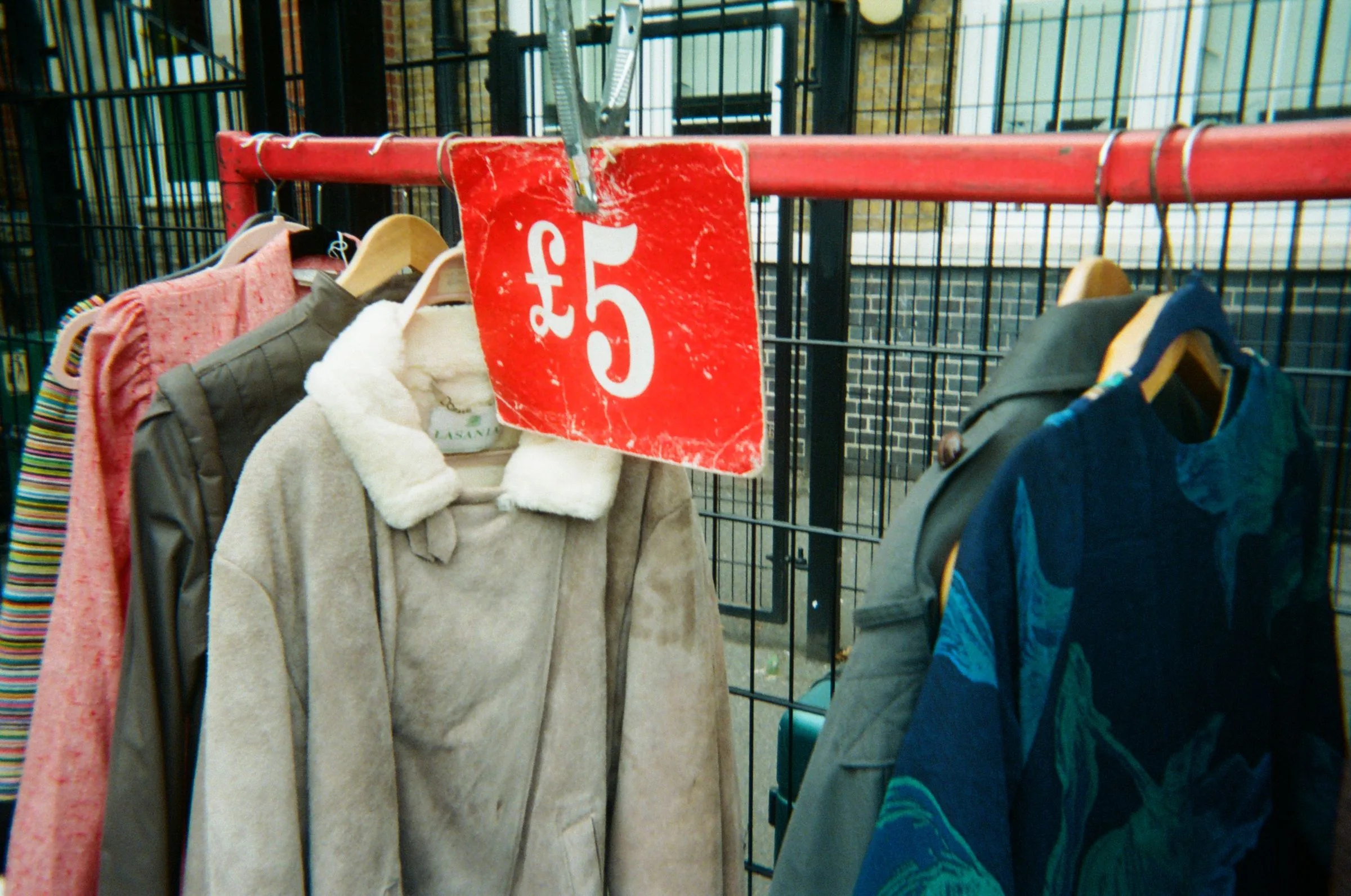 A £5 price tag hanging from a rail of coats at a market
