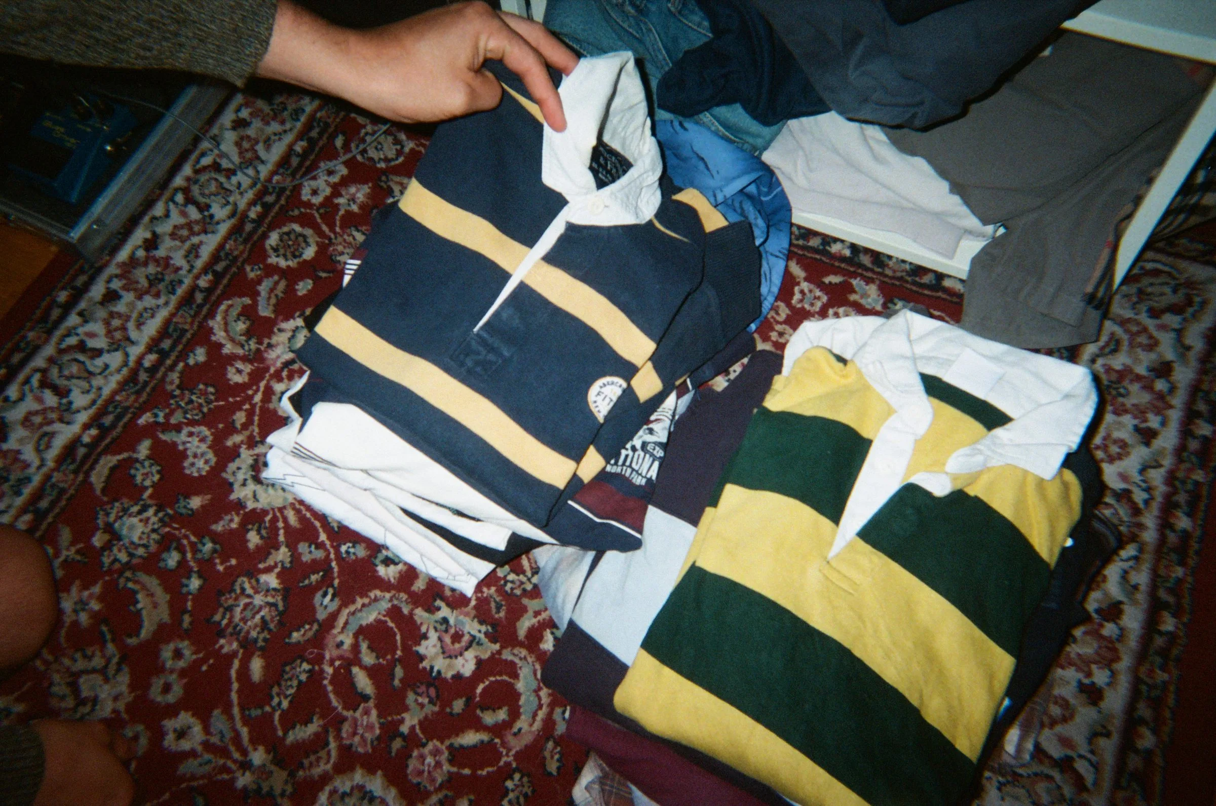 Striped rugby shirts folded out across a patterned rug