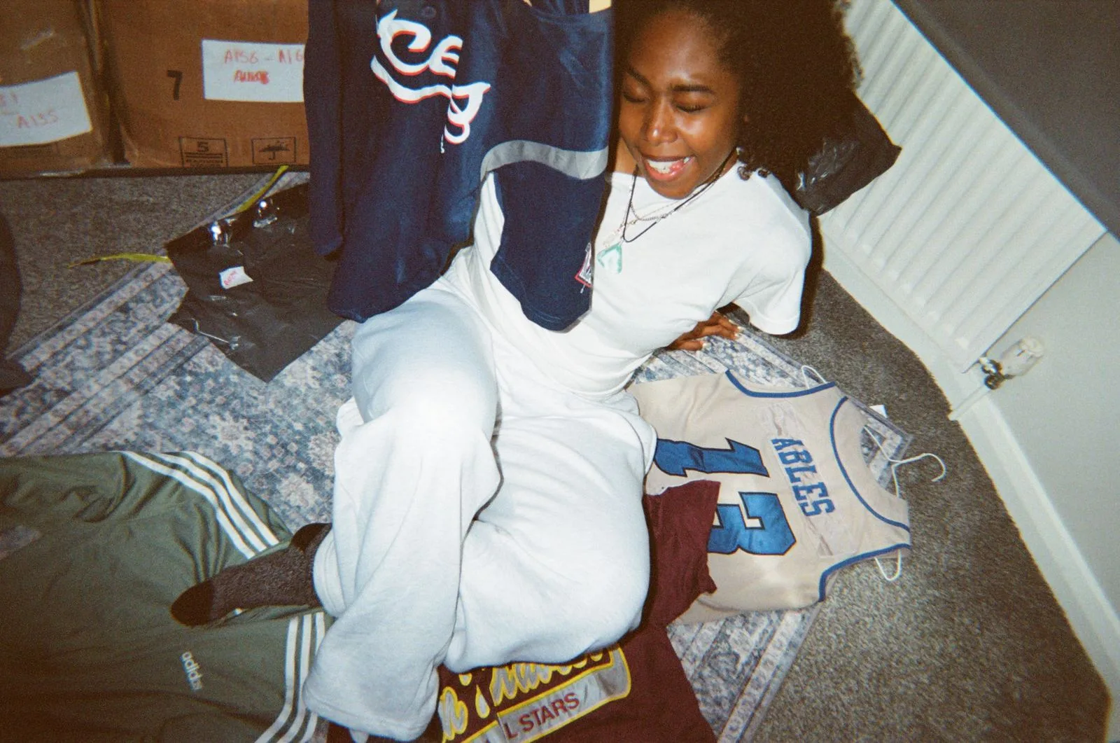 A young reseller sitting among sports jerseys and streetwear