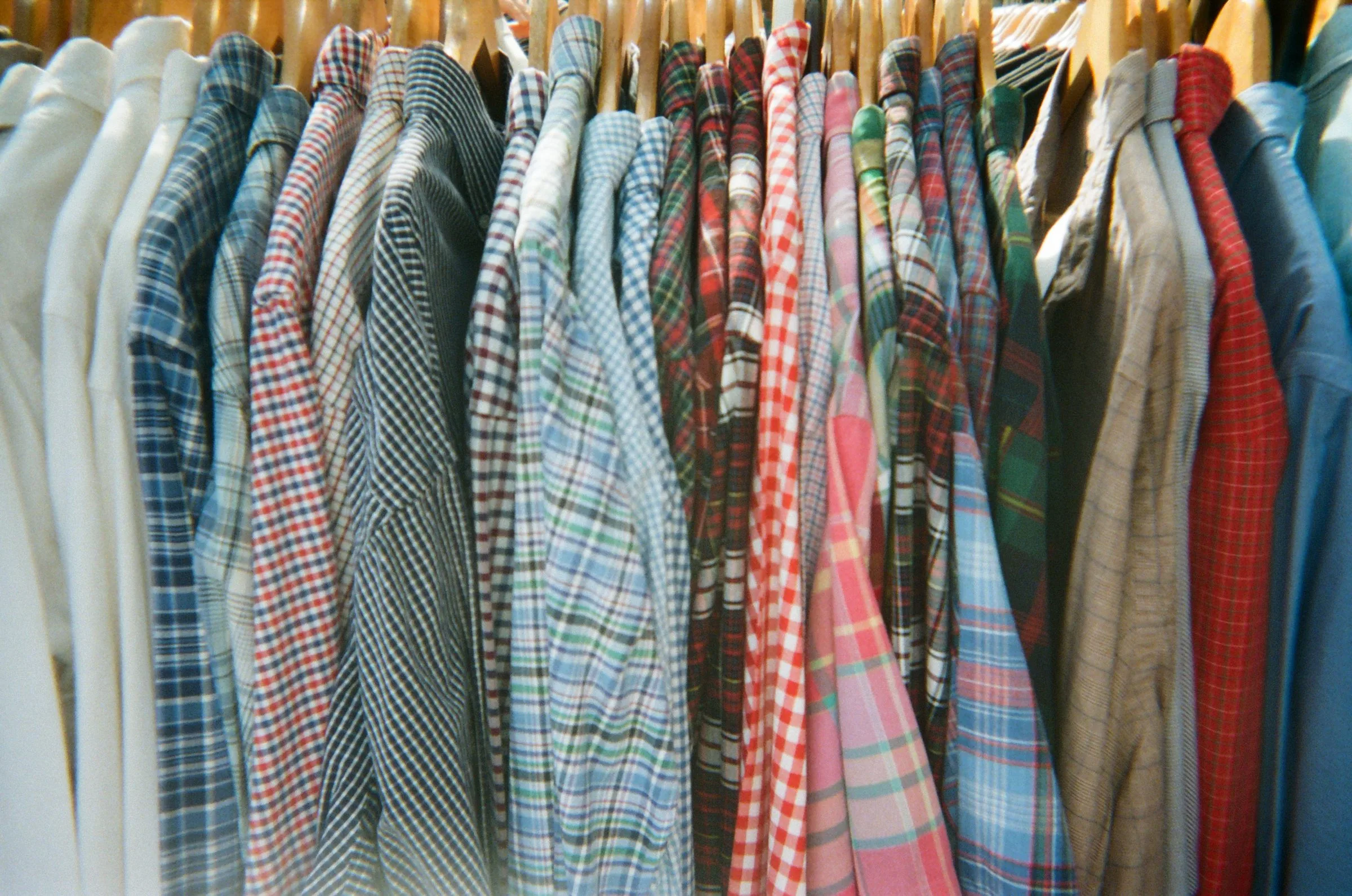 A rail packed with checked flannel shirts on wooden hangers