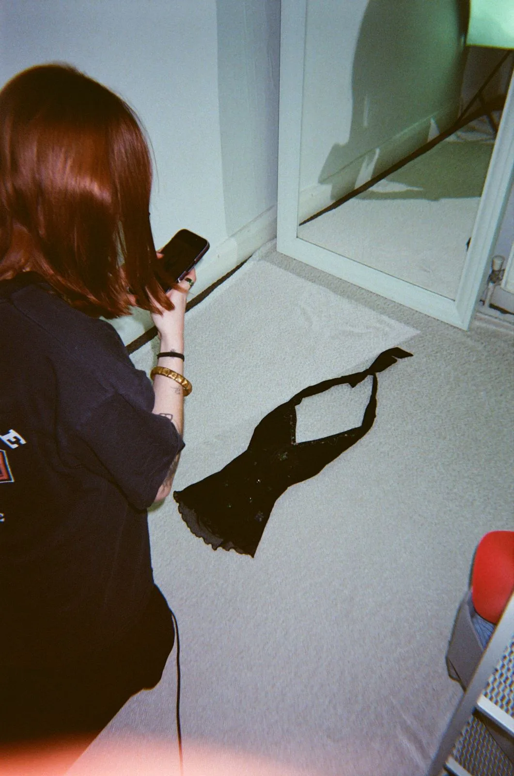 A reseller photographing a black garment pinned to the wall