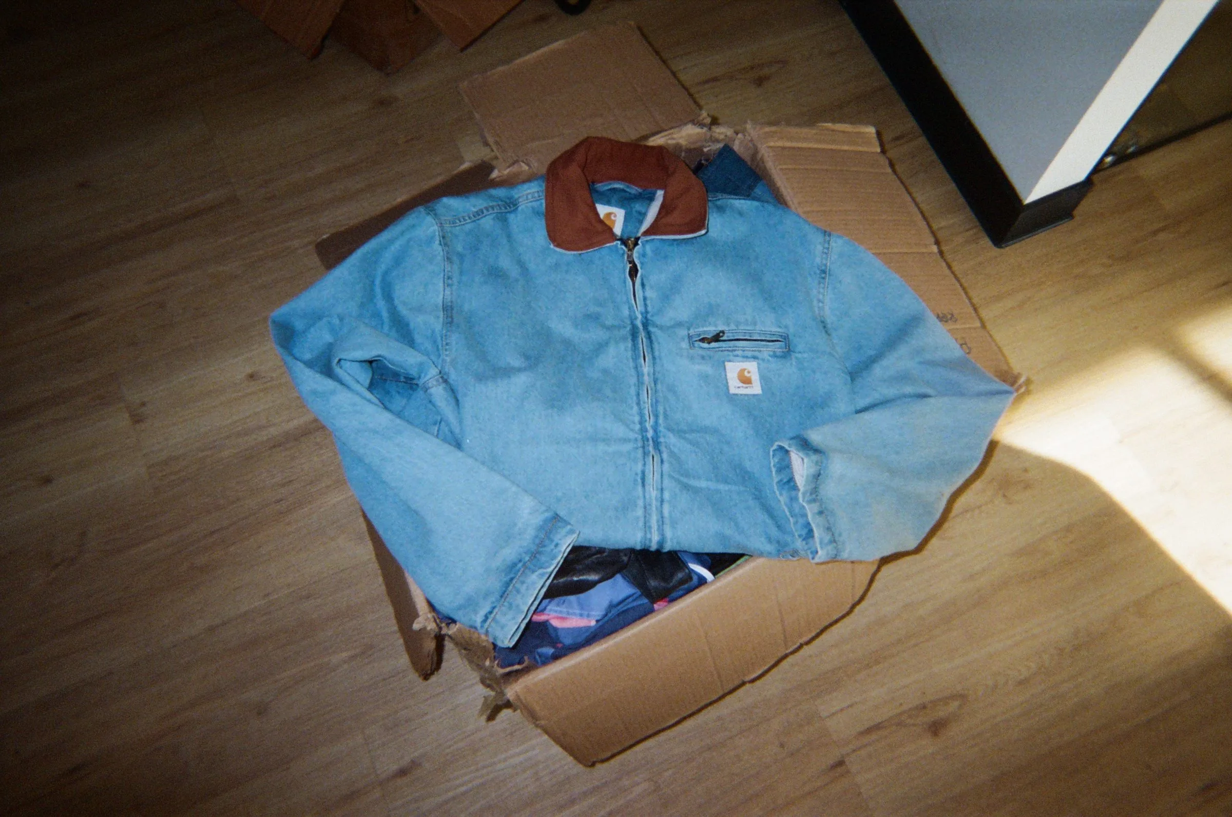 A Carhartt denim jacket folded on top of an open box of stock