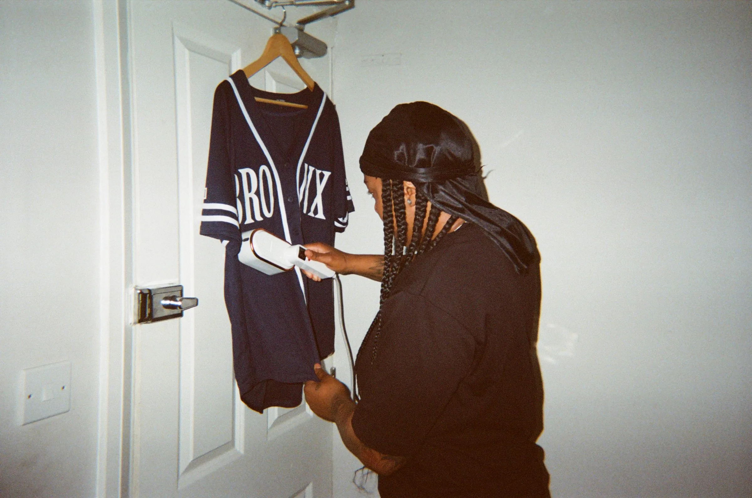 A reseller steaming a Bronx baseball jersey hanging on a door